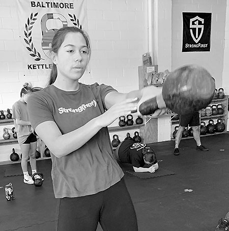 A young girl performing the one-arm kettlebell swing