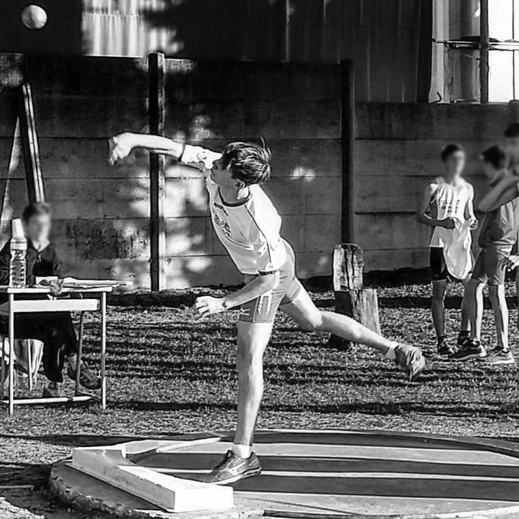 A young man performing the shot-put