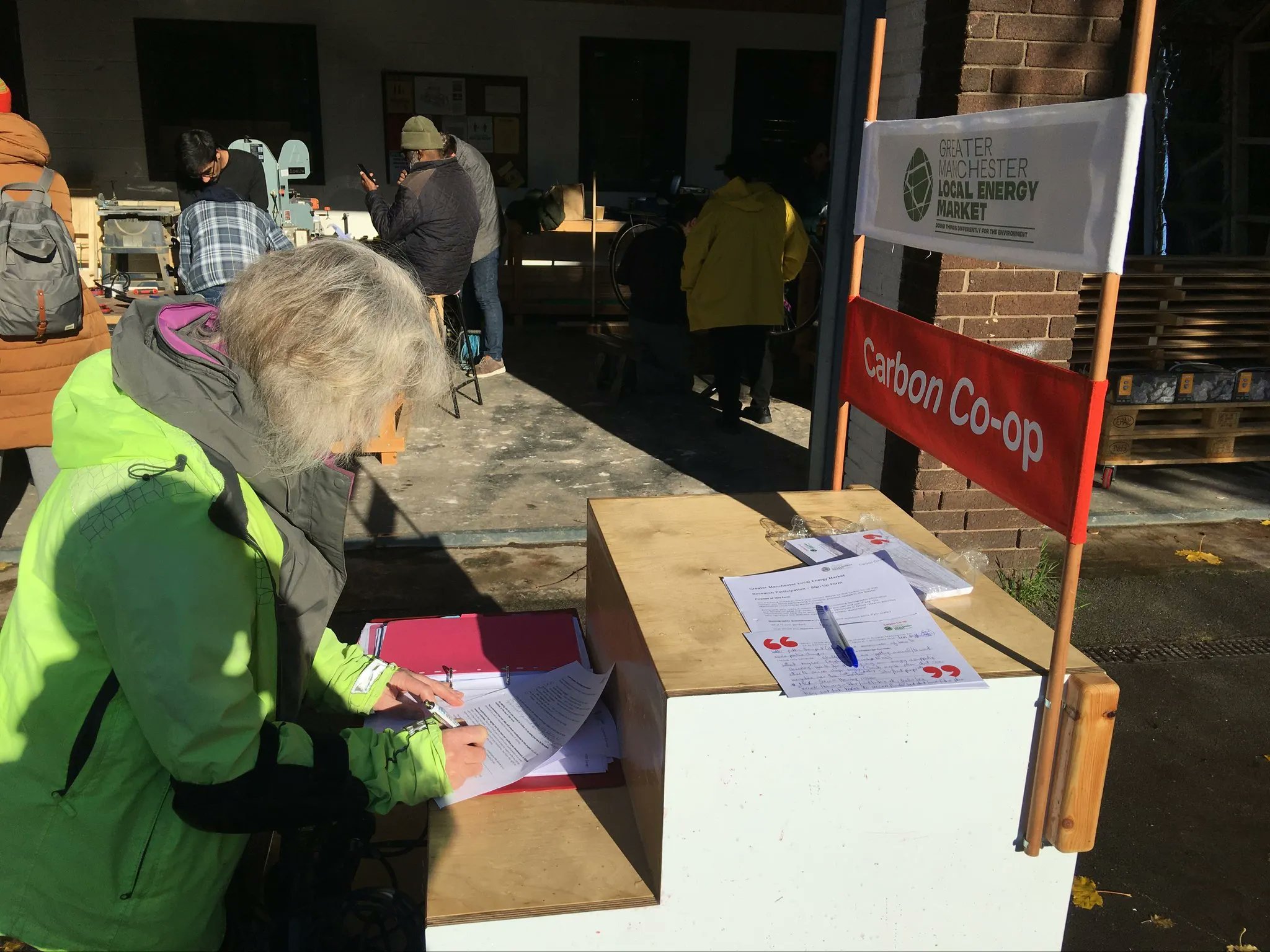 A woman signing up for a the Greater Manchester Local Energy Market Citizen's Jury on a Carbon Co-op stall