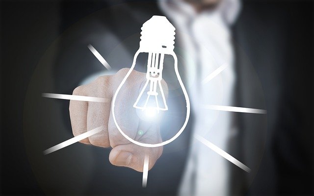 A photo of a finger touching an illustration of a lightbulb