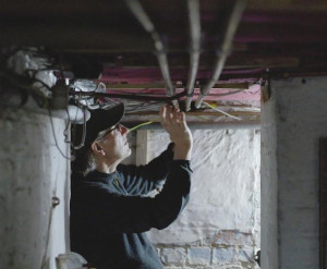 A photo of a man in a cellar working on underfloor insulation
