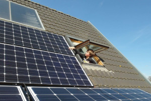 A child leaning out of a loft window looking at solar panels
