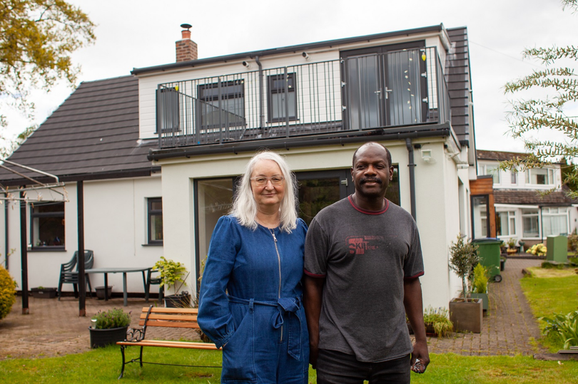 Photo of Sarah & Lloyd Hamilton in front of their 1960s bungalow