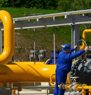 A photo of workers in blue overalls working on yellow pipe gas infrastructure