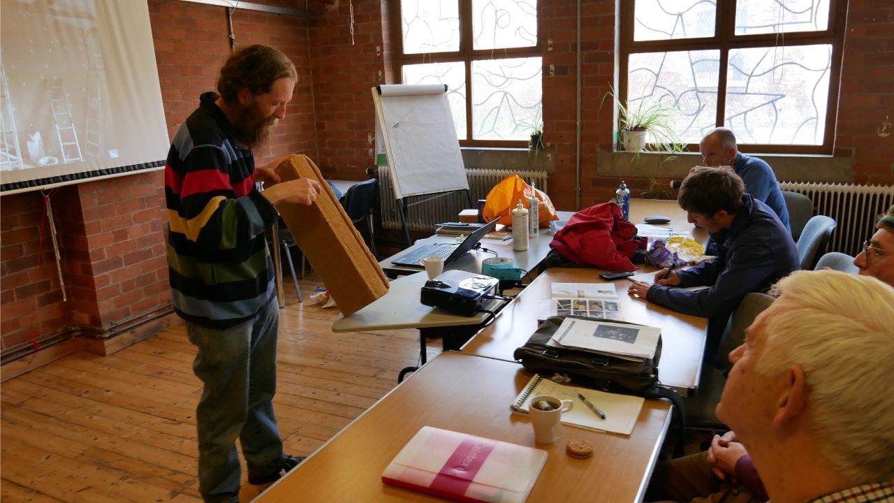 A photo of a man instructing a classroom about eco-renovation techniques
