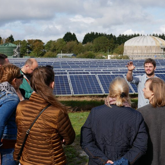 Photo of a group of people in front of a solar farm learning