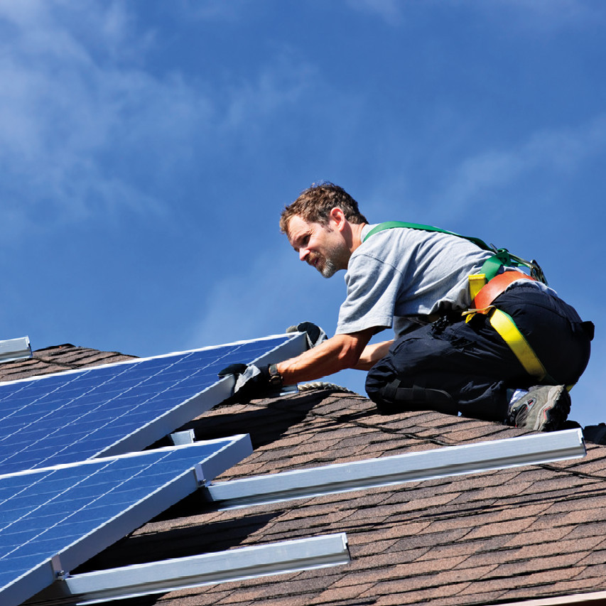 Photo of a man fitting solar panels to a roof