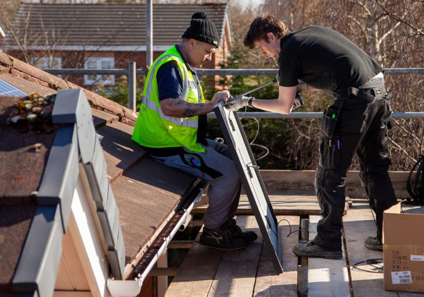 Two men installing solar panels on the roof of a house