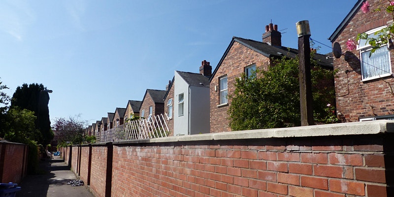 photo of rear of terrace houses from ginnel with one house with visible external wall insulation