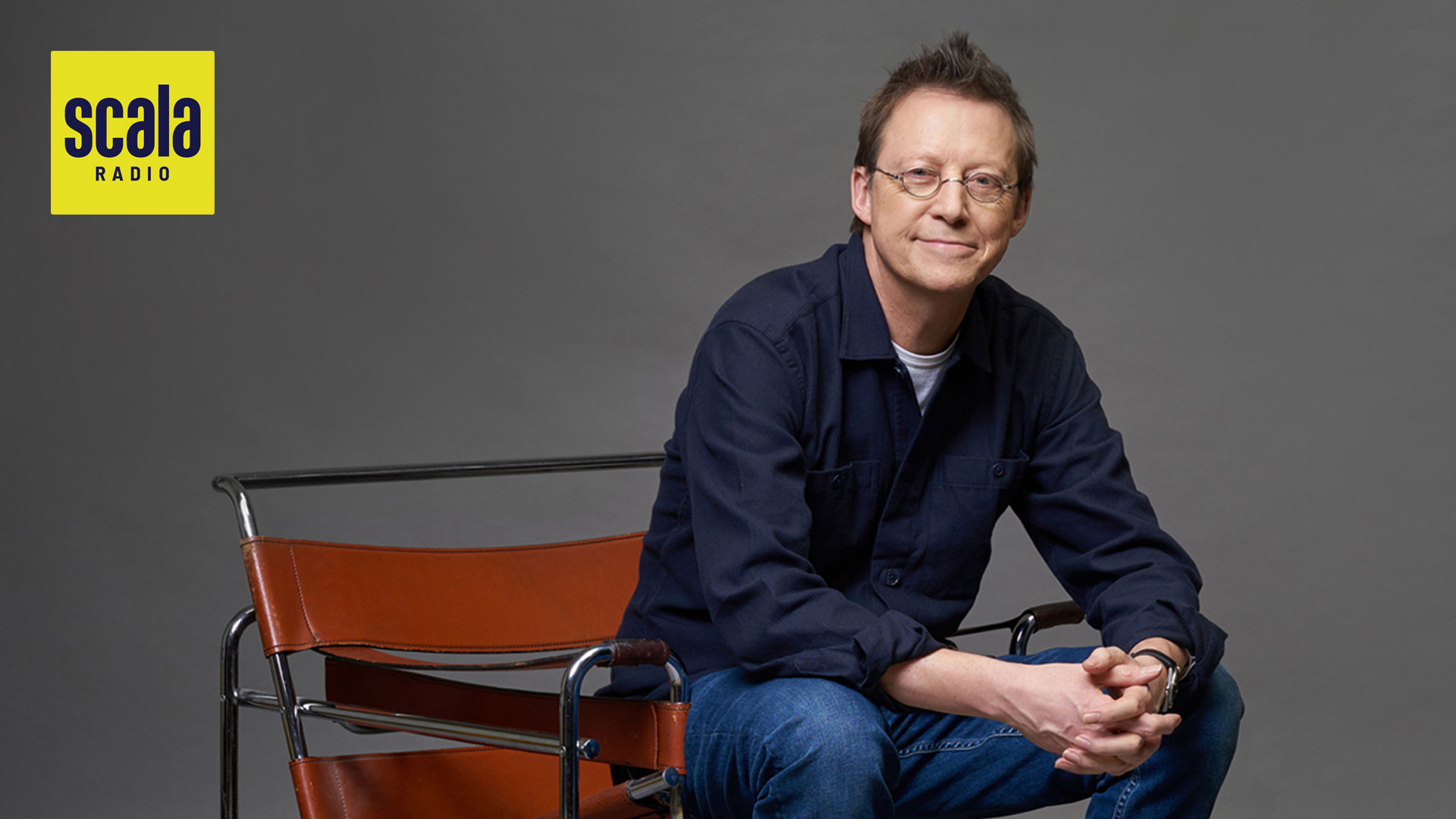 man sitting forward in a modern leather chair hands together in his lap