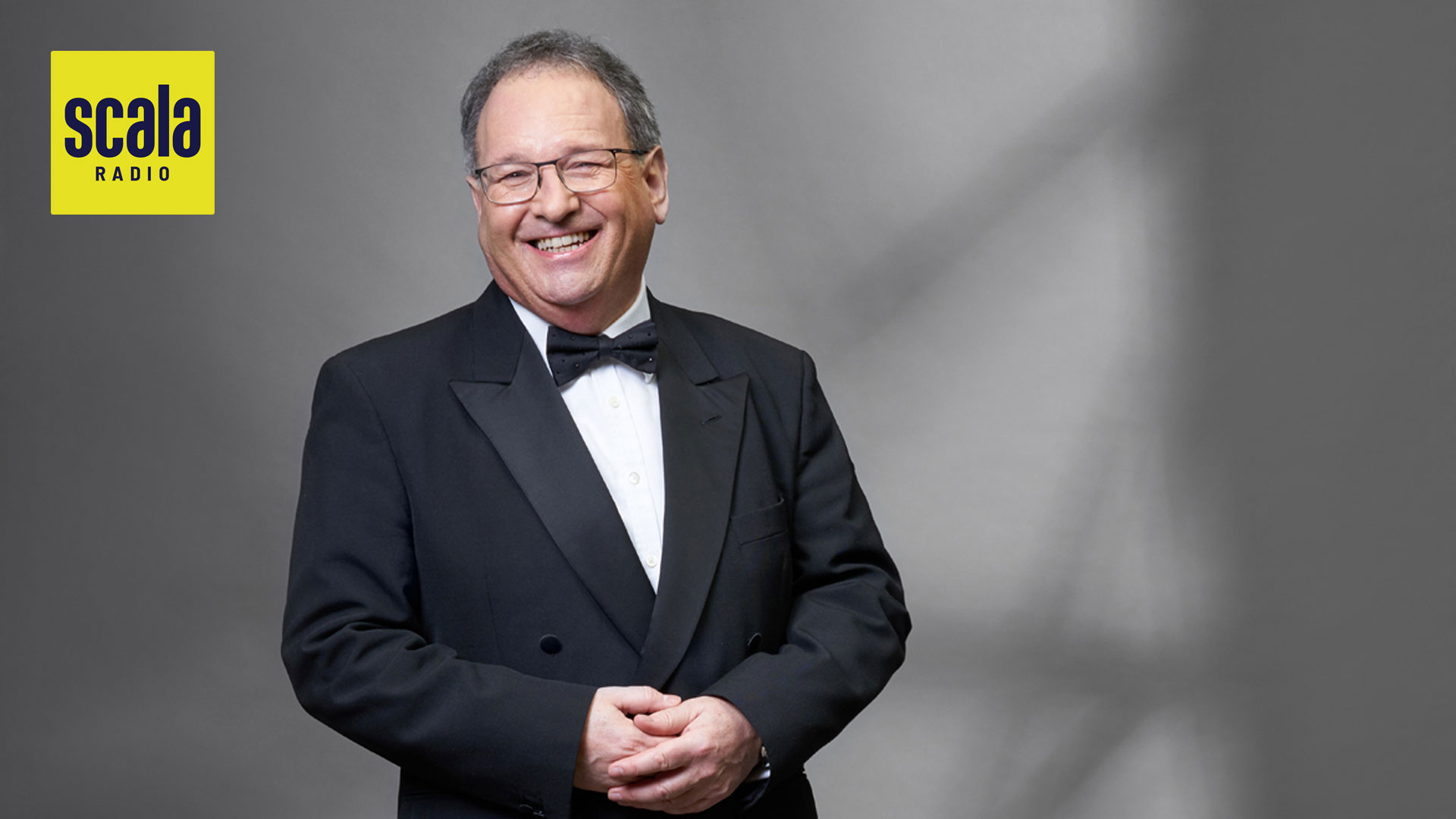 grey haired man in a dinner jacket smiling