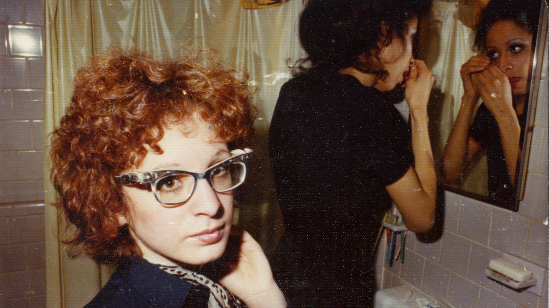 red haird woman standing next to a mirror in a bathroom