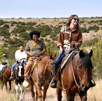 A group of people riding horseback through Palo Duro Canyon.