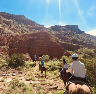 A group of people take a tour of Palo Duro Canyon on horseback.