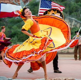 A performer in a colorful folkorico costume dances in a musical performance during the TEXAS Outdoor Musical.