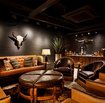 The interior of Royal Bar with lounge chairs, a sofa, and a longhorn skull hanging on the wall.